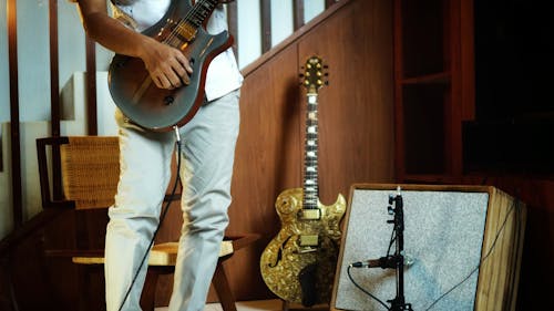 Person in White Pants Playing Electric Guitar