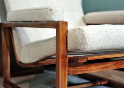Detailed close-up of a contemporary wooden armchair with soft beige cushions, highlighting its sleek design.