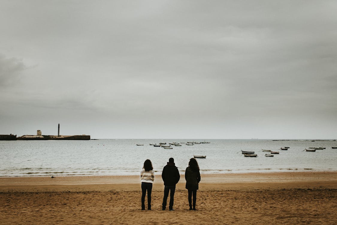 Three Person Standing Near the Seashore