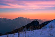 宁静的日落在白雪覆盖的山上，用橙色和粉红的色调描绘出一片充满活力的天空