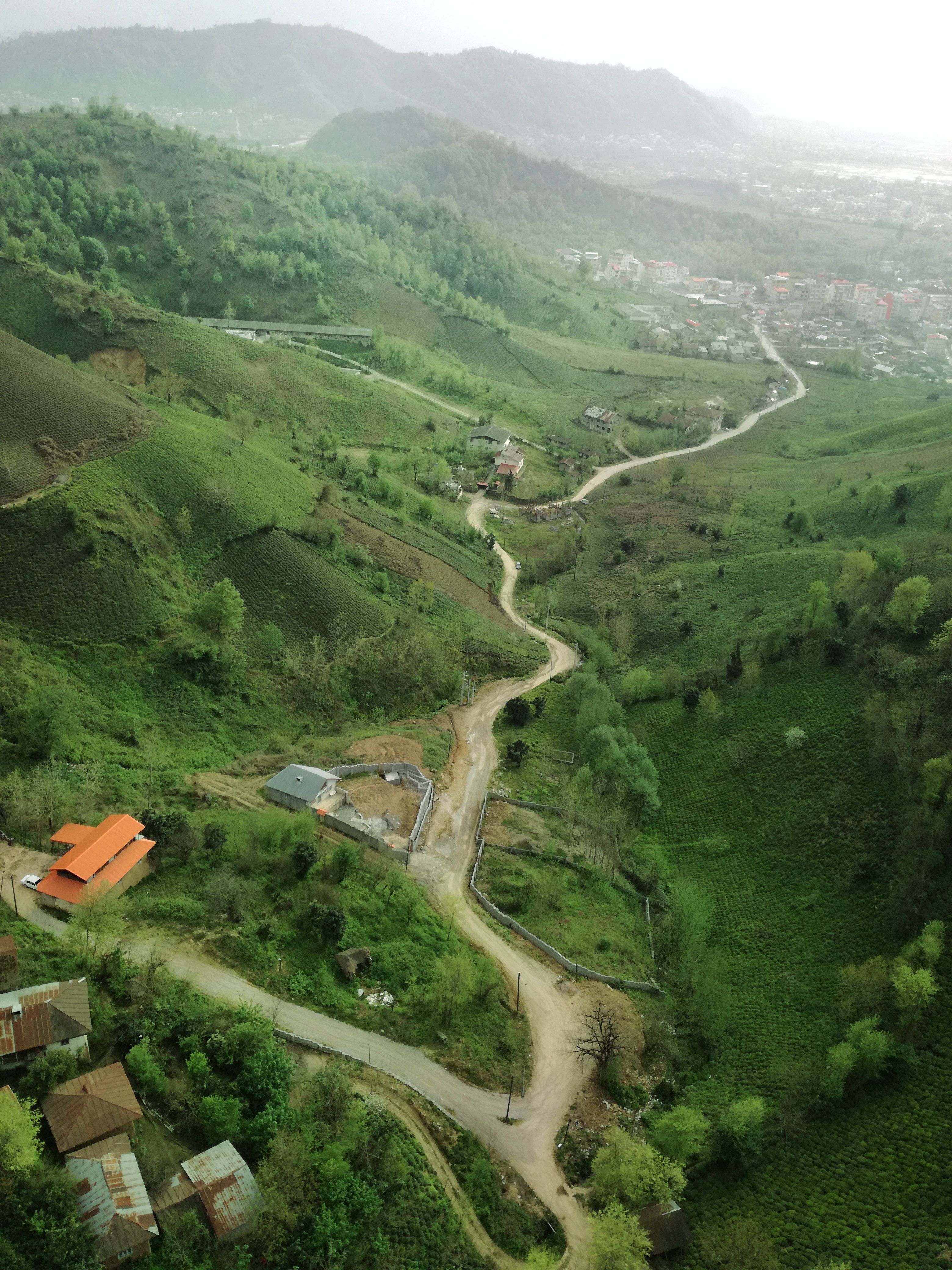 Scenic aerial view of winding roads and lush green hills in Iran's countryside, capturing nature's beauty.