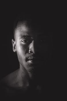 Artistic black and white portrait of a man with dramatic lighting and expressive gaze.