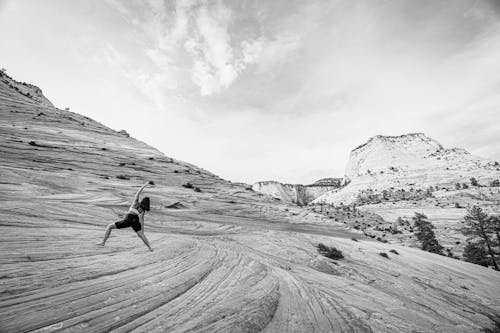 
A Grayscale of a Woman Doing Yoga Poses on a Hill