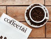 一个质朴的布置，包括一杯咖啡豆和一本放在木桌上的咖啡主题杂志