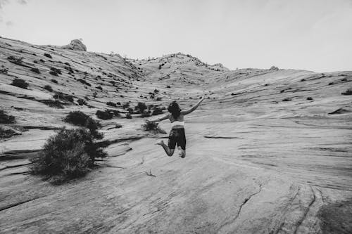 

A Grayscale of a Woman in an Activewear Jumping