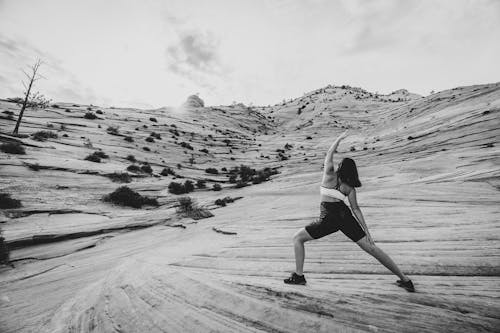 Grayscale Photo of a Woman Working Out in the Desert