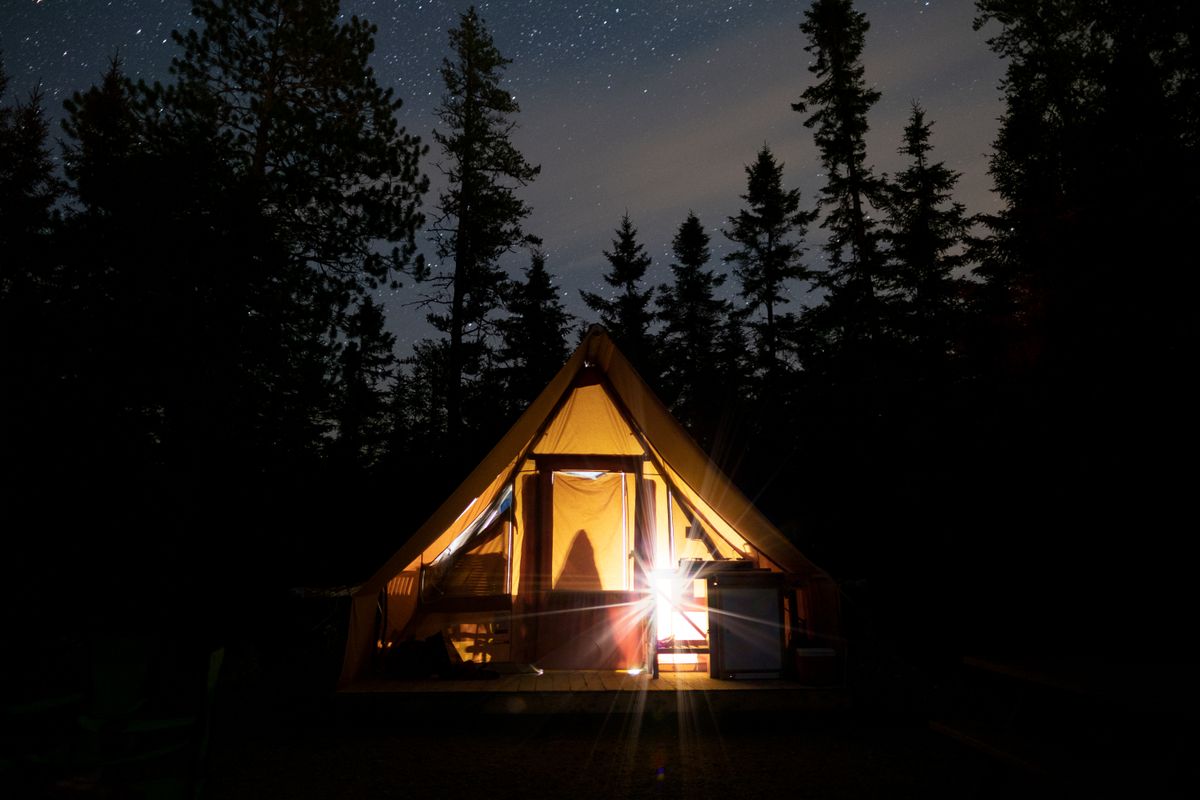 Tent glowing under a starry night sky in a Canadian forest