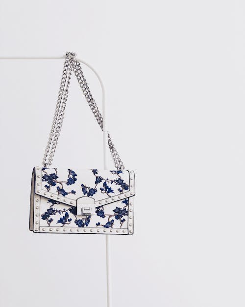 Free White and Blue Floral Flap Sling Bag Hanging on White Steel Rack Stock Photo