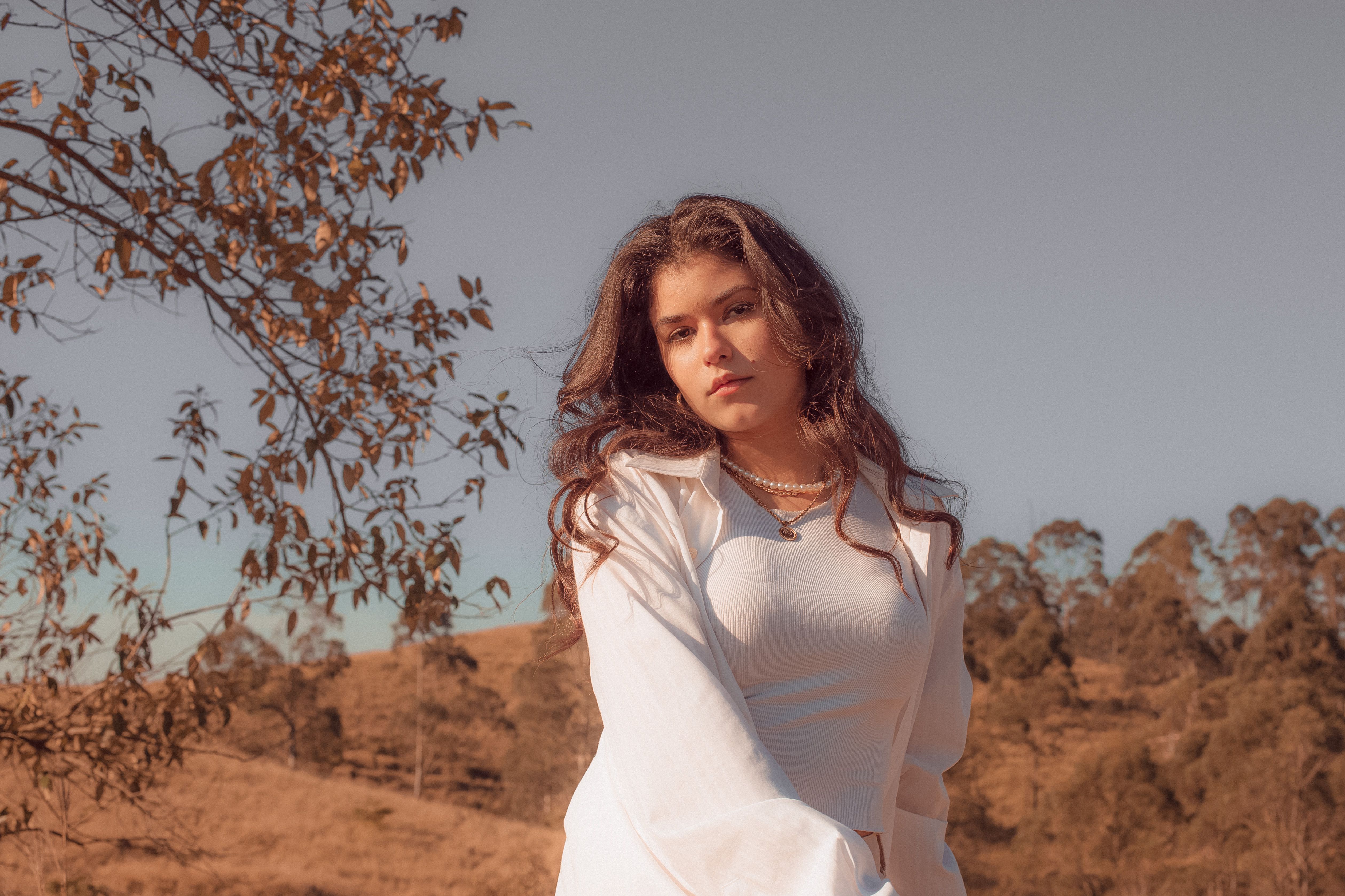 Woman in White Long Sleeve Shirt Standing Near Brown Tree · Free Stock ...