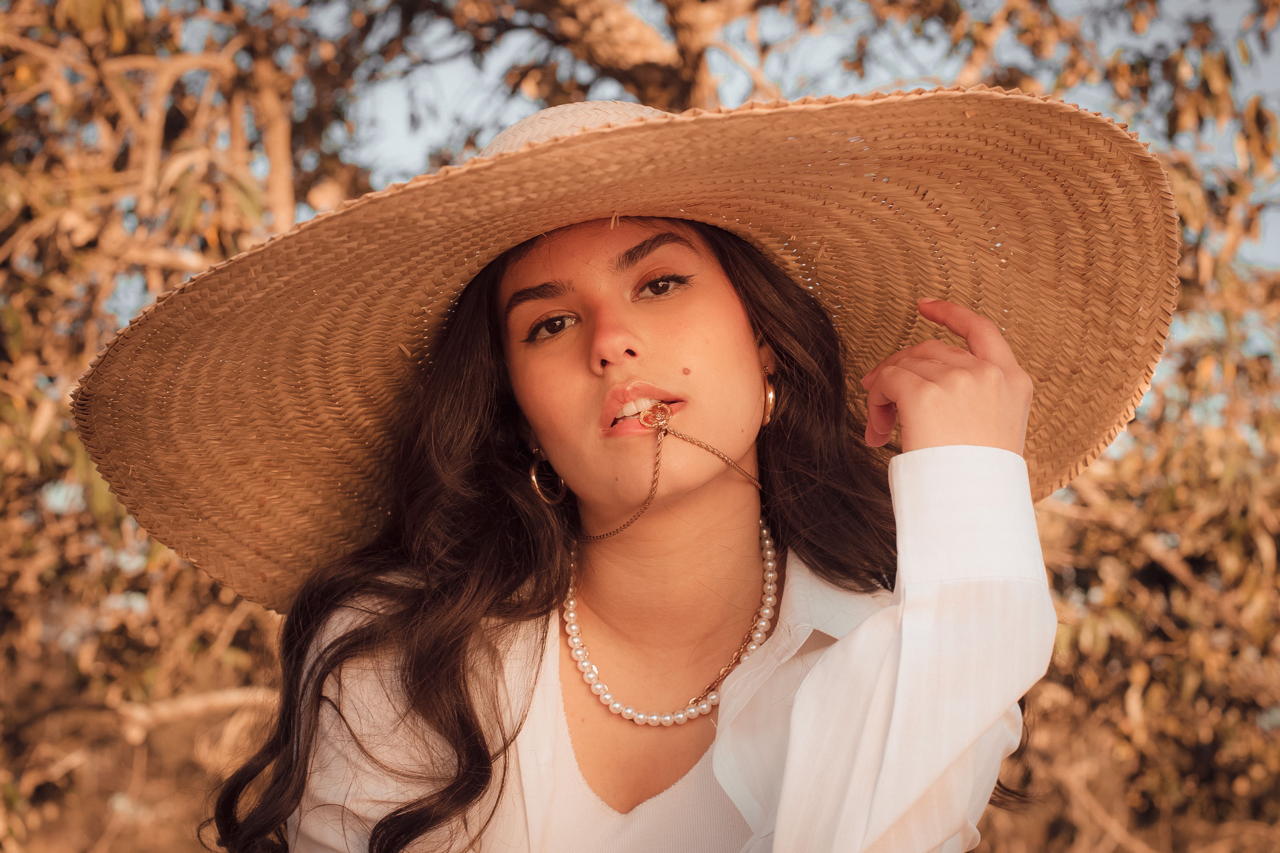 Woman in White Long Sleeve Shirt Wearing Brown Woven Hat · Free Stock Photo
