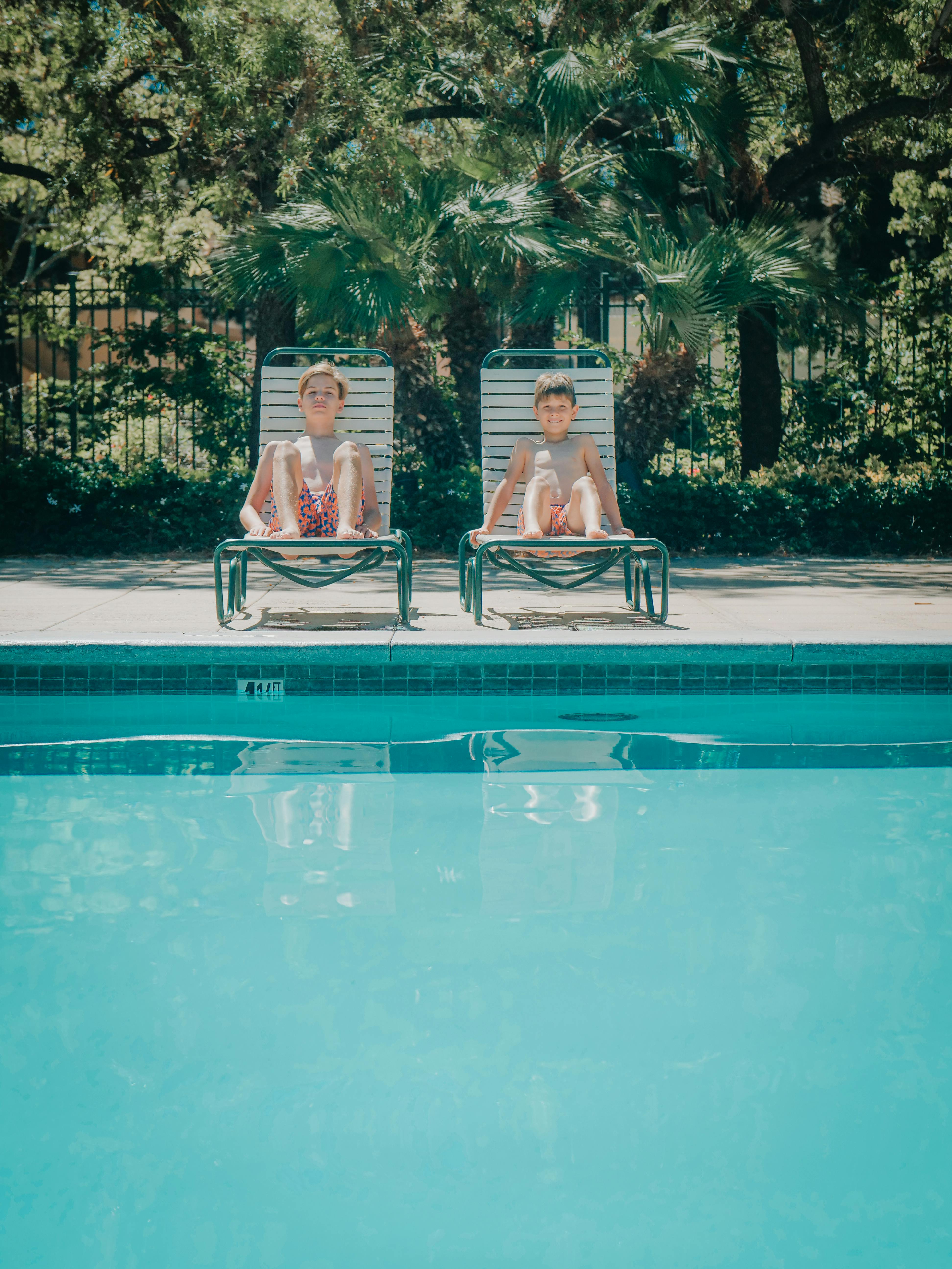 boys sitting beside the swimming pool