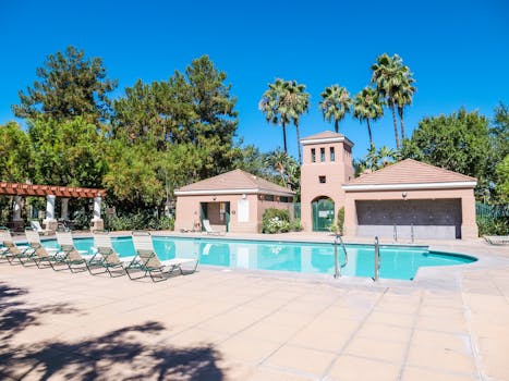 A serene poolside setting with sun loungers under a vibrant blue sky, perfect for relaxation.