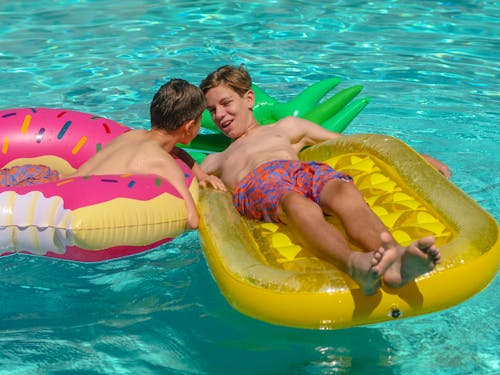 Two Boys In A Pool With Inflatable Swim Rings