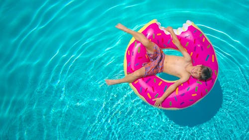 Free Kid Lying on a Inflatable Floater on the Swimming Pool Stock Photo