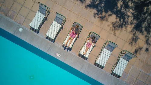 Free Aerial shot of children sunbathing on lounge chairs by a swimming pool. Stock Photo