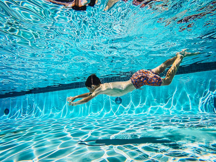 Kids Swimming Underwater In A Pool