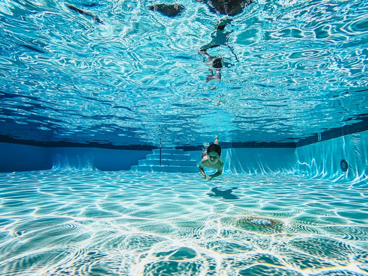 Kid Swimming Under A Pool