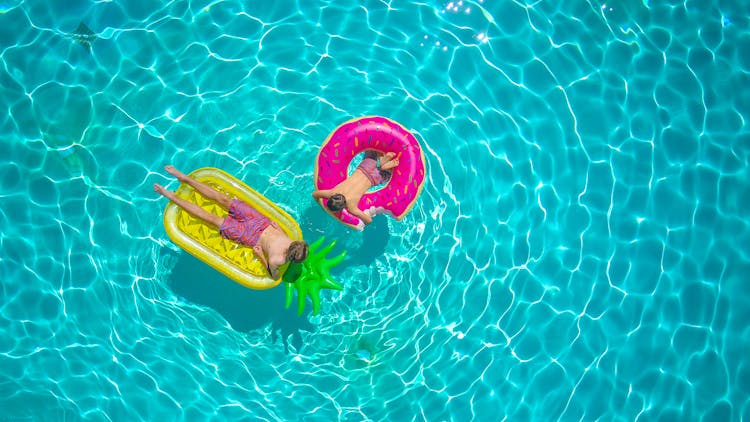 Brothers Lying On Floaters On A Swimming Pool