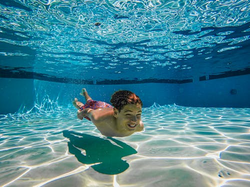 Shirtless Kid Swimming Under Water