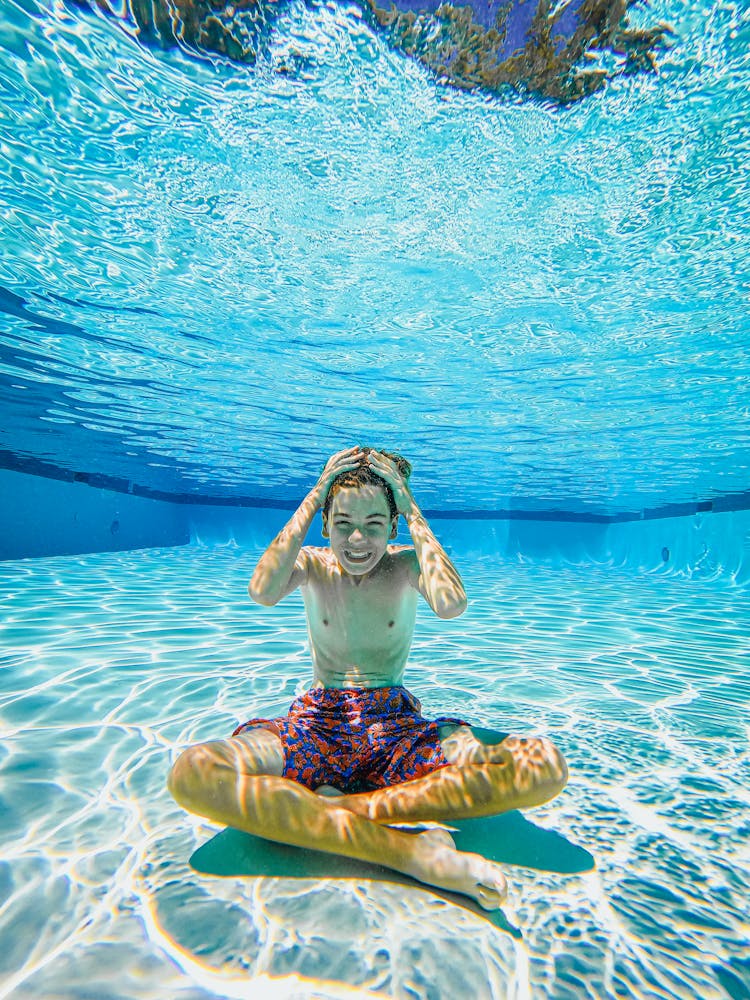 Kid Sitting Underwater In A Swimming Pool