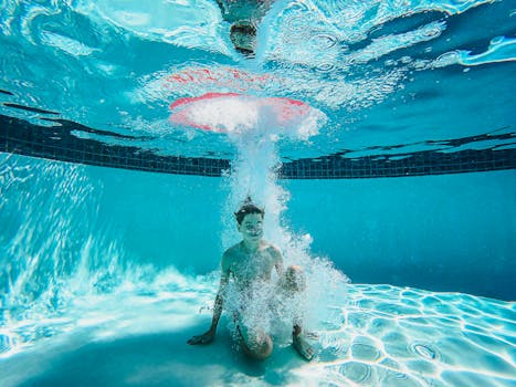A boy enjoys underwater playtime in a clear swimming pool, surrounded by bubbles.
