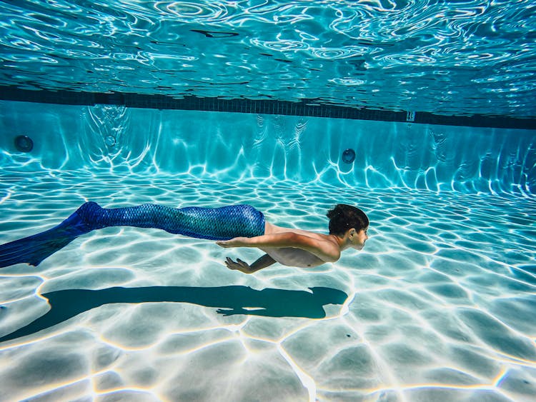 A Kid Swimming Wearing Blue Mermaid Tail 