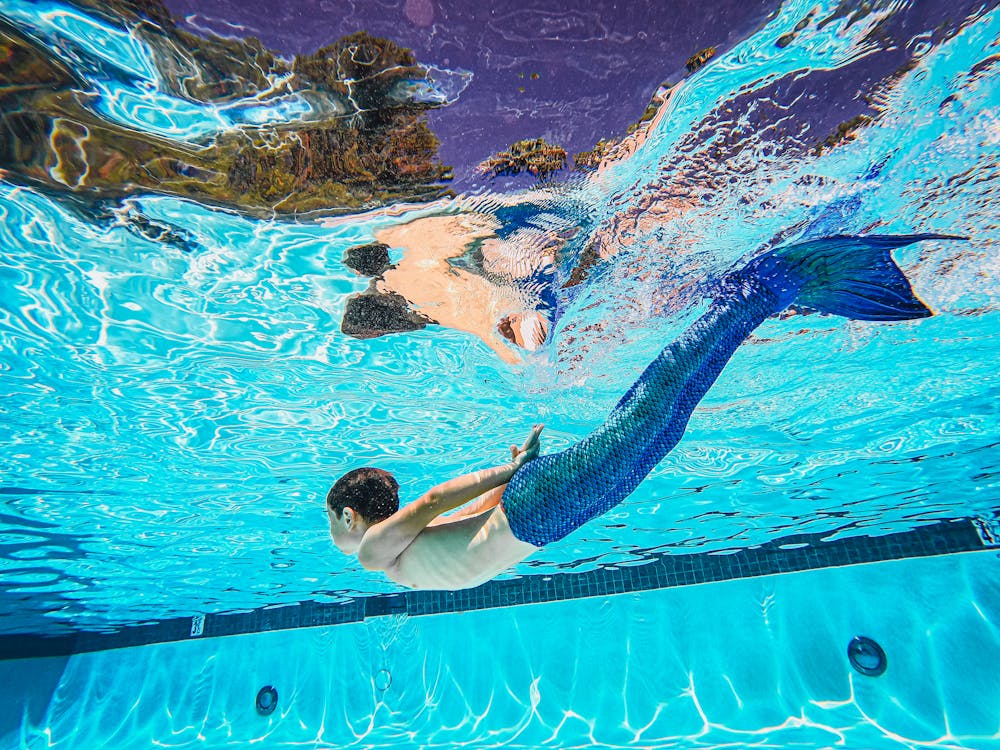 Shirtless Person Wearing a Mermaid Suit Swimming