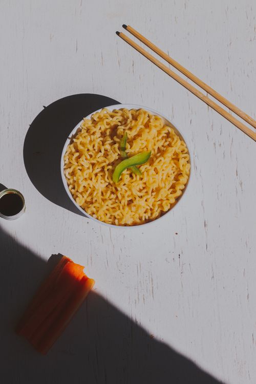 Free A vibrant bowl of Asian noodles garnished with vegetables, shot top view with chopsticks. Stock Photo