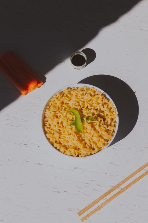 Free Top view of macaroni with bell pepper slice on a white surface, sunny setting. Stock Photo