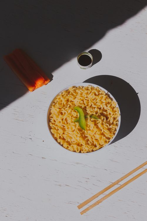 Free Appetizing ramen noodles in a bowl with chopsticks, shadow play, vibrant setting. Stock Photo