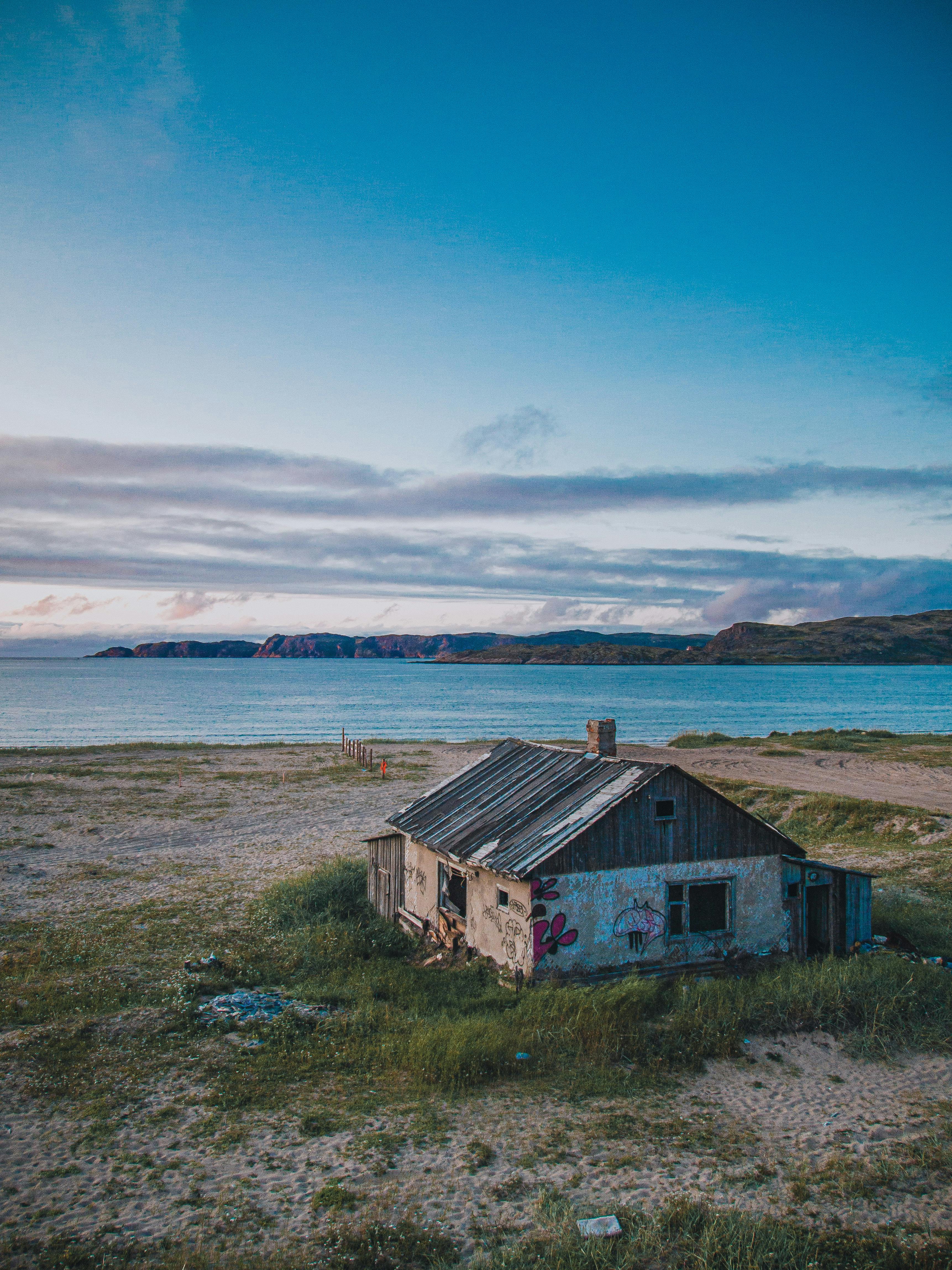 An abandoned house by a scenic coastline, perfect travel destination image with vibrant sky.
