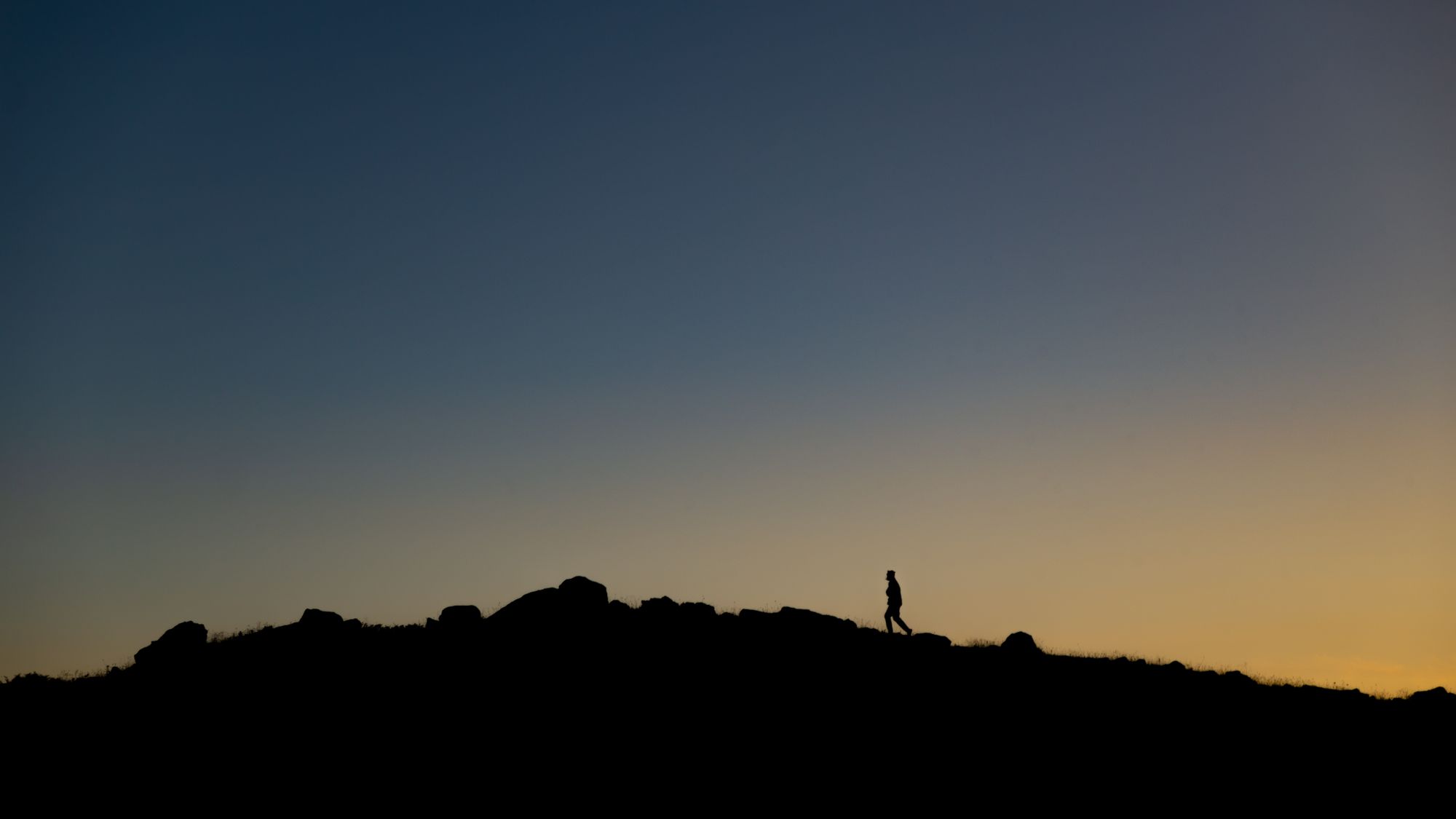 A lone figure walking a ridgeline against a clear dusk sky, photo by Dimka Nevedimka on Pexels