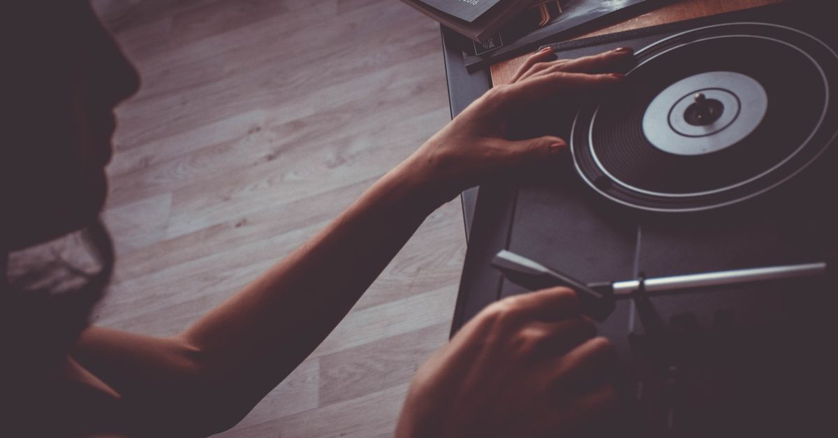 A person holding a smashed vinyl record with a look of regret, dark studio lighting