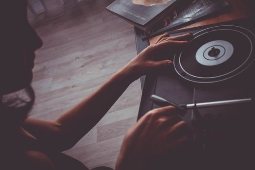 A person playing a vinyl record on a vintage turntable, creating a nostalgic mood.