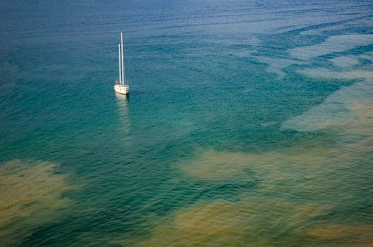 A serene aerial shot of a sailboat on the calm ocean waters, highlighting tranquility and solitude.