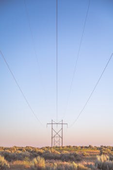 Scenic view of power lines stretching across a countryside under a clear blue sky.