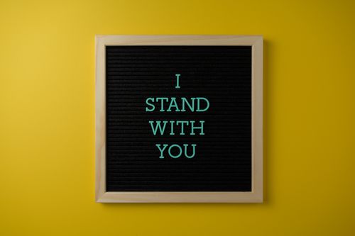 Free A motivational quote 'I Stand With You' on a board against a yellow surface. Stock Photo