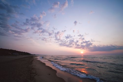 Free A peaceful beach view with a beautiful sunset and gentle waves at the shoreline. Stock Photo