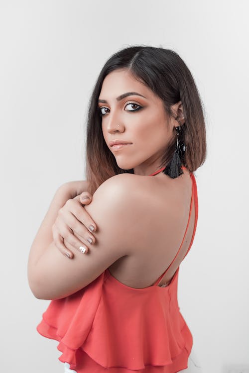 Photo of a Woman in a Pink Top Posing with Her Hand on Her Arm