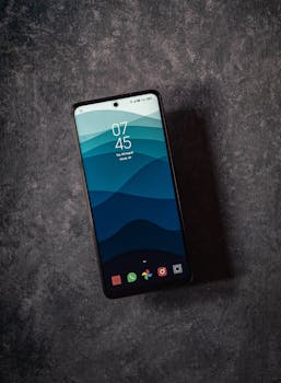 Elegant flatlay featuring a smartphone displaying 07:45 AM on a textured dark surface, emphasizing modern design.