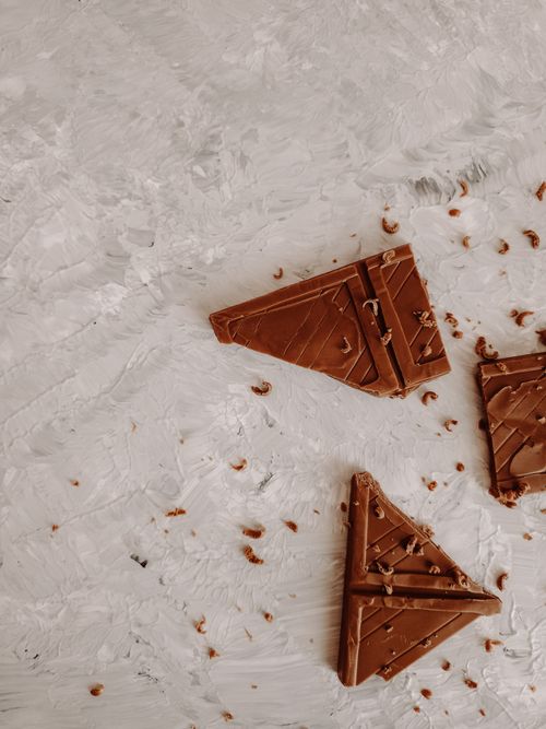 Free Close-up of broken chocolate pieces on a light, textured surface. Perfect for dessert-themed presentations. Stock Photo