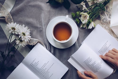 Witte Keramische Theekop Met Schotel Bij Twee Boeken Boven Grijze Bloemen Textiel