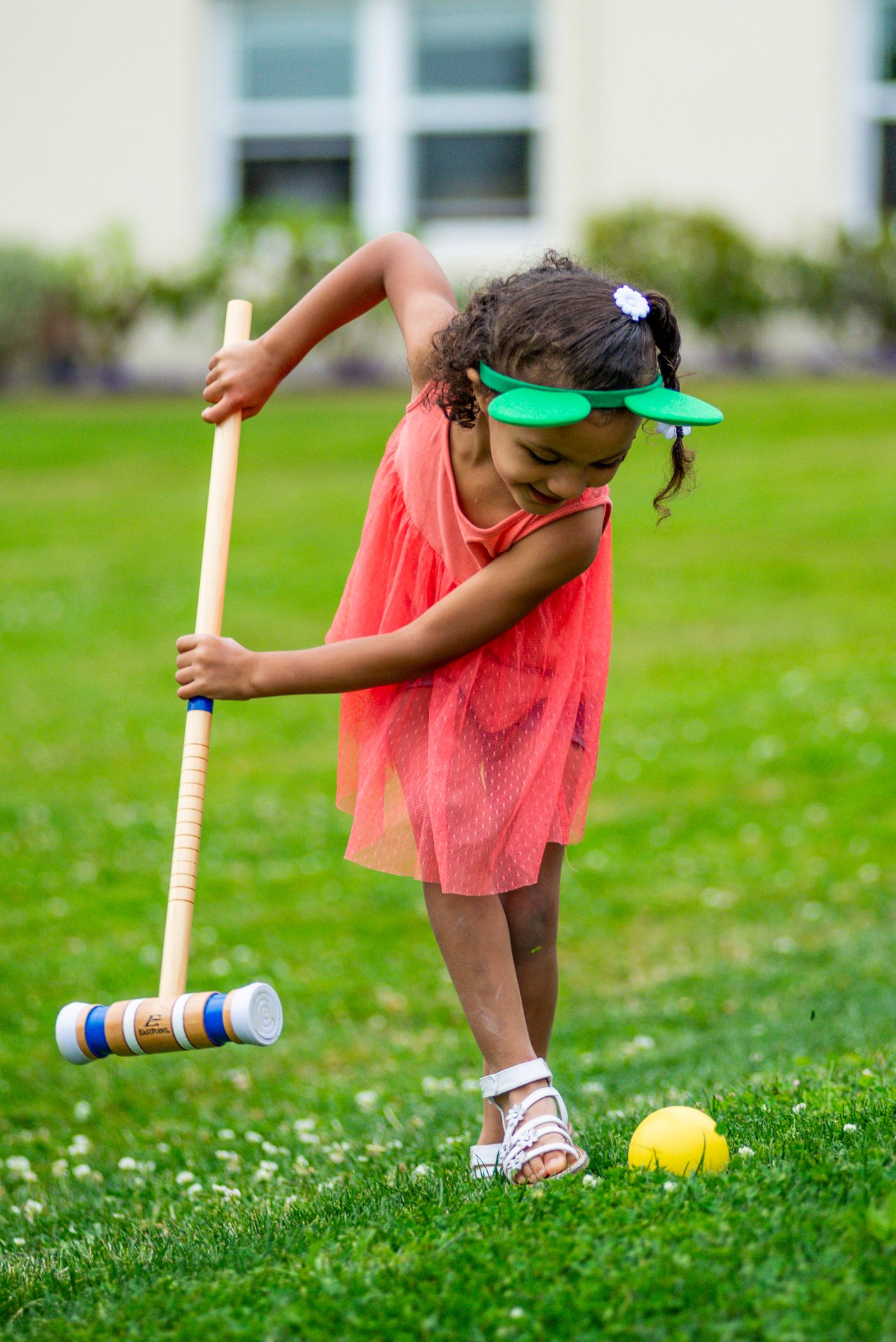 Child playing croquet with a mallet on green grass