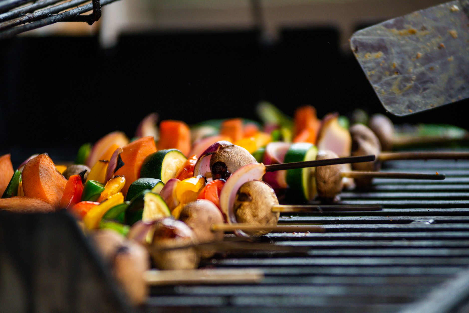 Grilled vegetables sizzling in a metal grill basket