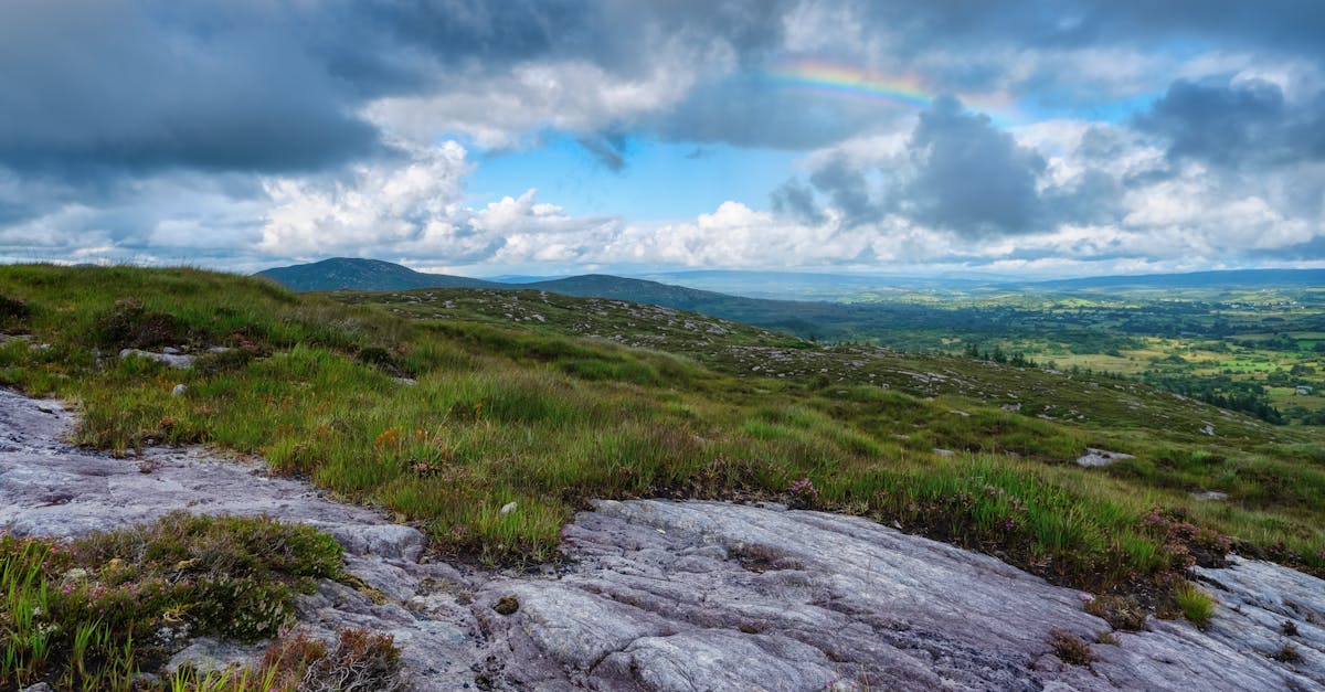 Breathtaking landscape view of Sligo, Ireland with a rainbow over lush greenery and rocky terrain.
