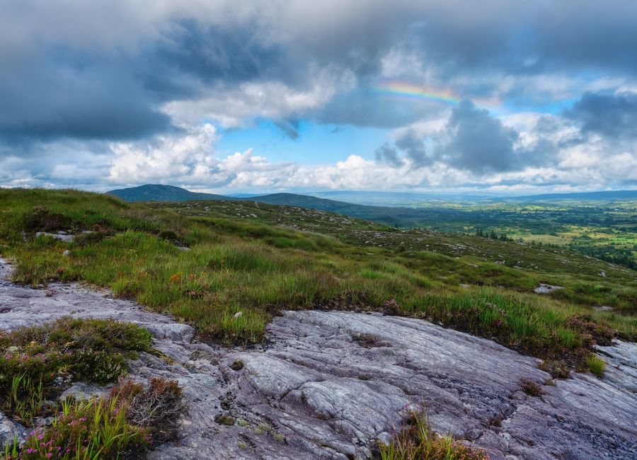 Breathtaking landscape view of Sligo, Ireland with a rainbow over lush greenery and rocky terrain.