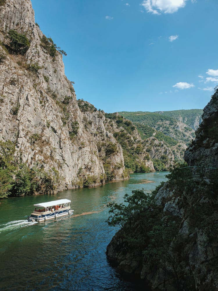 Motor Boat Cruising On River Near Rocky Mountain