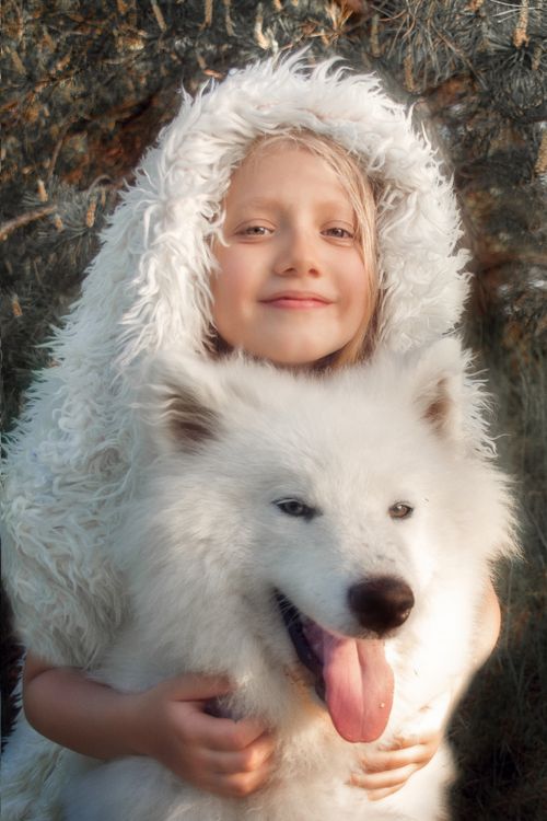 Free Adorable child with a fluffy white dog outdoors, both smiling at the camera. Perfect companionship image. Stock Photo