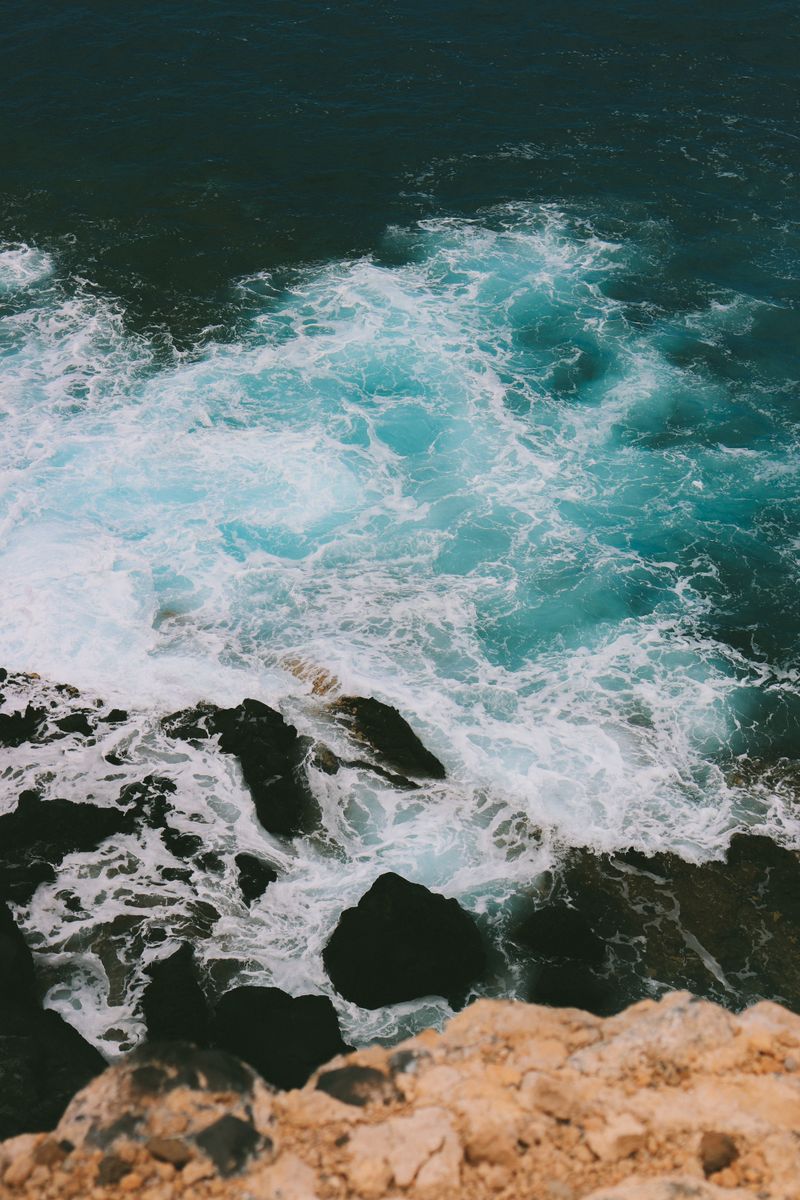 Vivid capture of ocean waves splashing against rocks, showcasing the sea's raw energy and beauty.