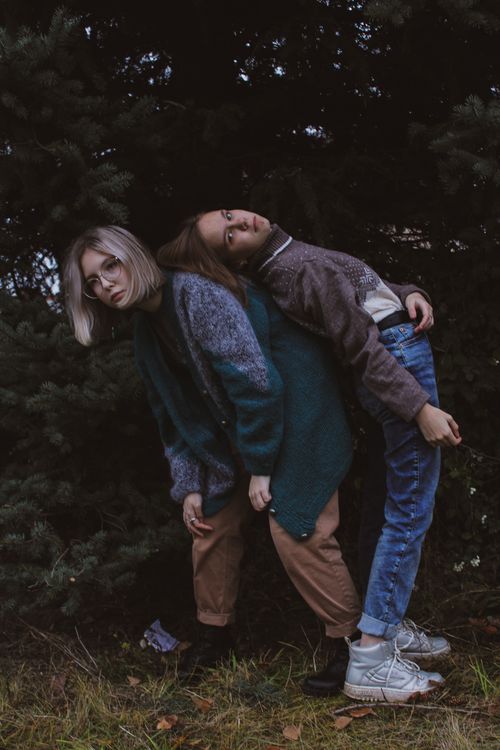 Free Creative portrait of two young women in a unique pose, set against an outdoor backdrop. Stock Photo
